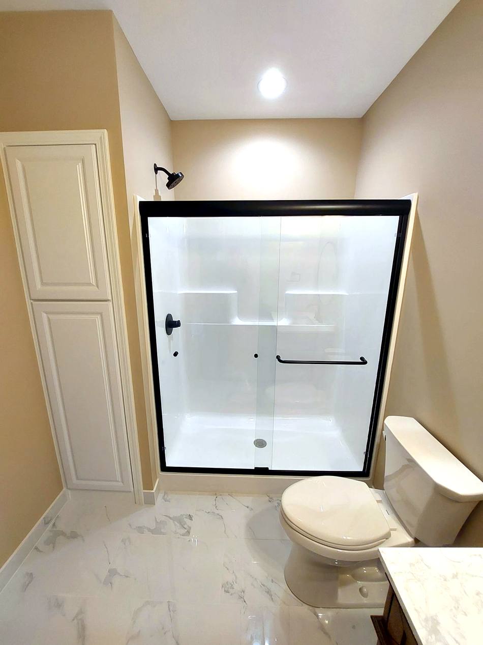 Remodeled bathroom with glass shower and marble-look floor