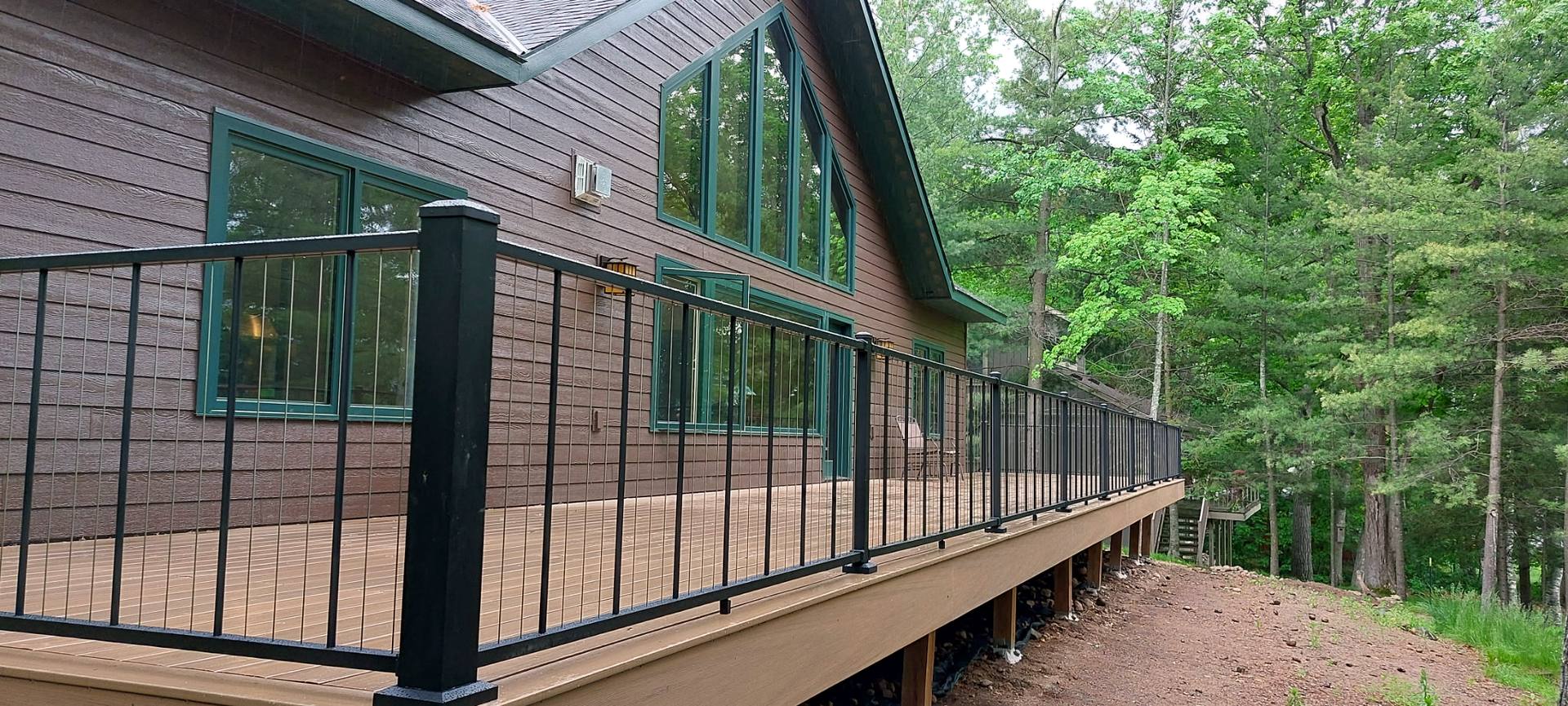 Elevated composite deck with black railing on a wooded Minnesota home built by MN Best Construction